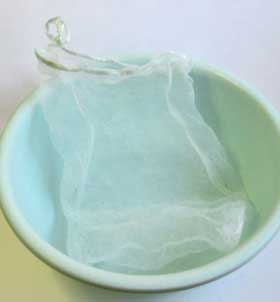 洗面器の中に置いたタデアイの葉を濾すアミの袋